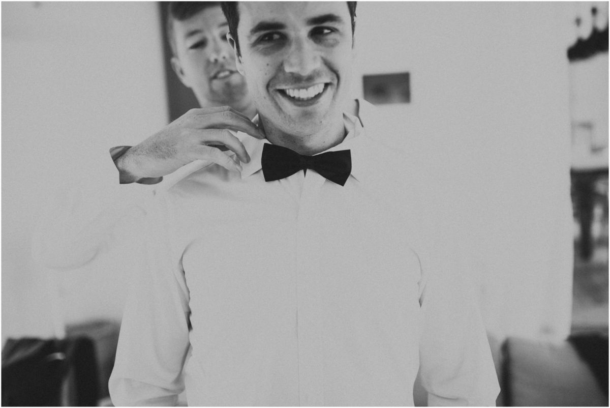 Groomsman helping the groom with his bow tie