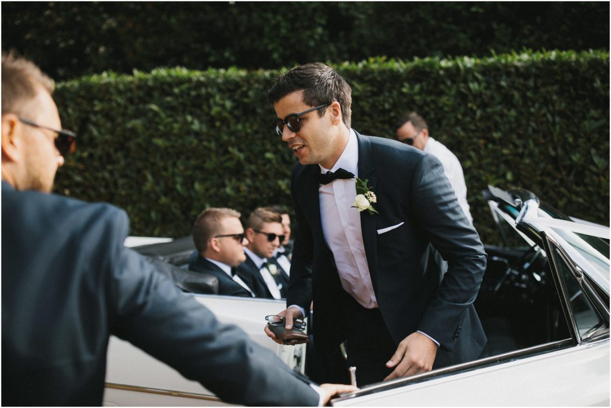 Groom gets out of old Cadillac at his Bendooley Berrima wedding