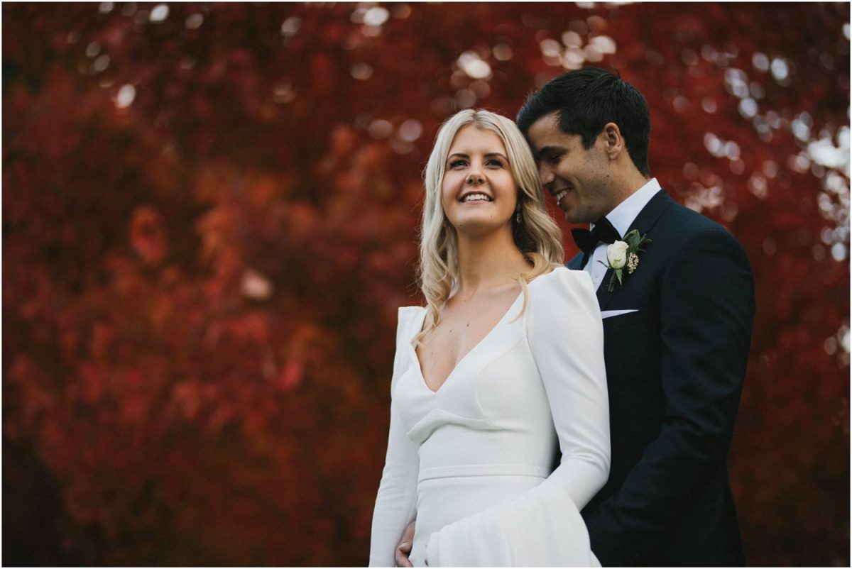 Bride and groom pose against autumn colours