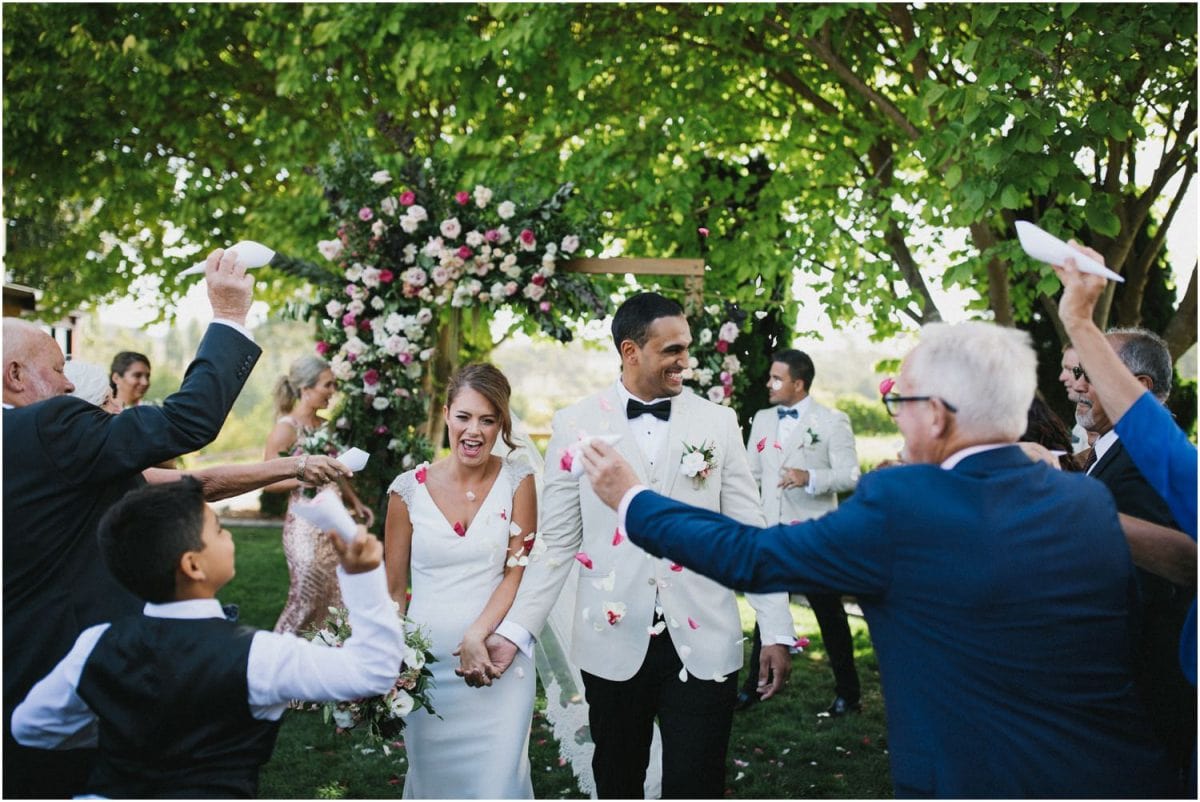 A bride and groom walk down the aisle with confetti being thrown at them at a Centennial Vineyards Bowral wedding