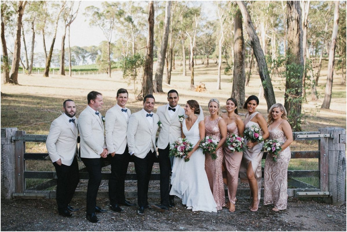A bridal party in front of an old wooden gate at a Centennial Vineyards Bowral wedding