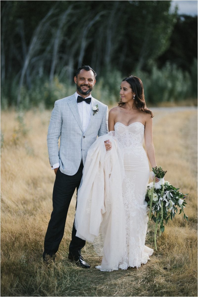 A bride and groom pose for a photo after their Wanaka wedding. The groom is wearing a beautiful Inbal Dror gown. 