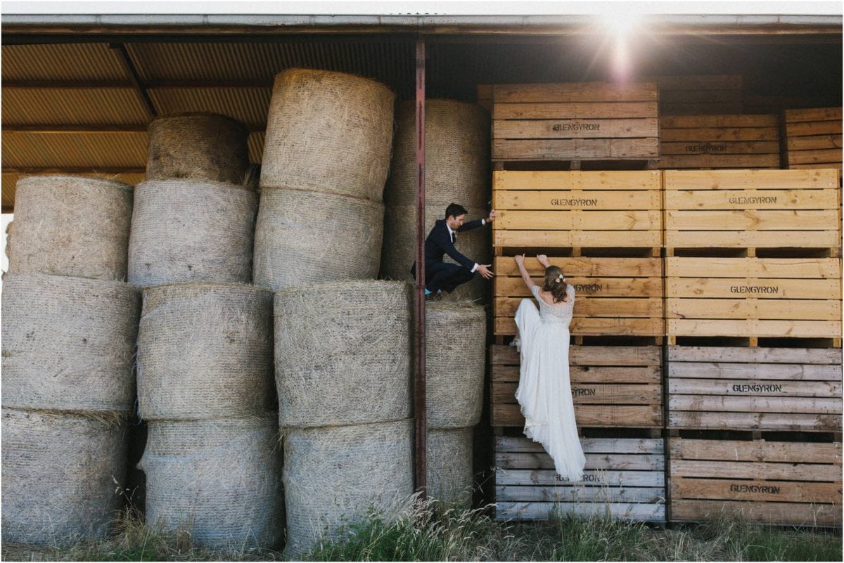 A newly married couple climb some hay bales after their Aghadoe Estate wedding