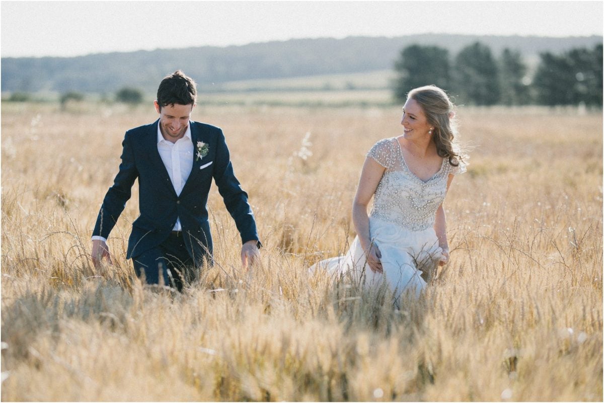 A newly married couple walk through a field of wheat after their Aghadoe Estate wedding
