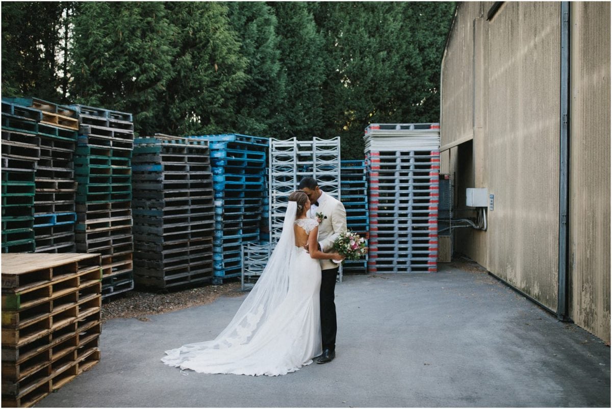 A bride and groom pose for a photo near some wine pallets after their Centennial Vineyards Bowral wedding