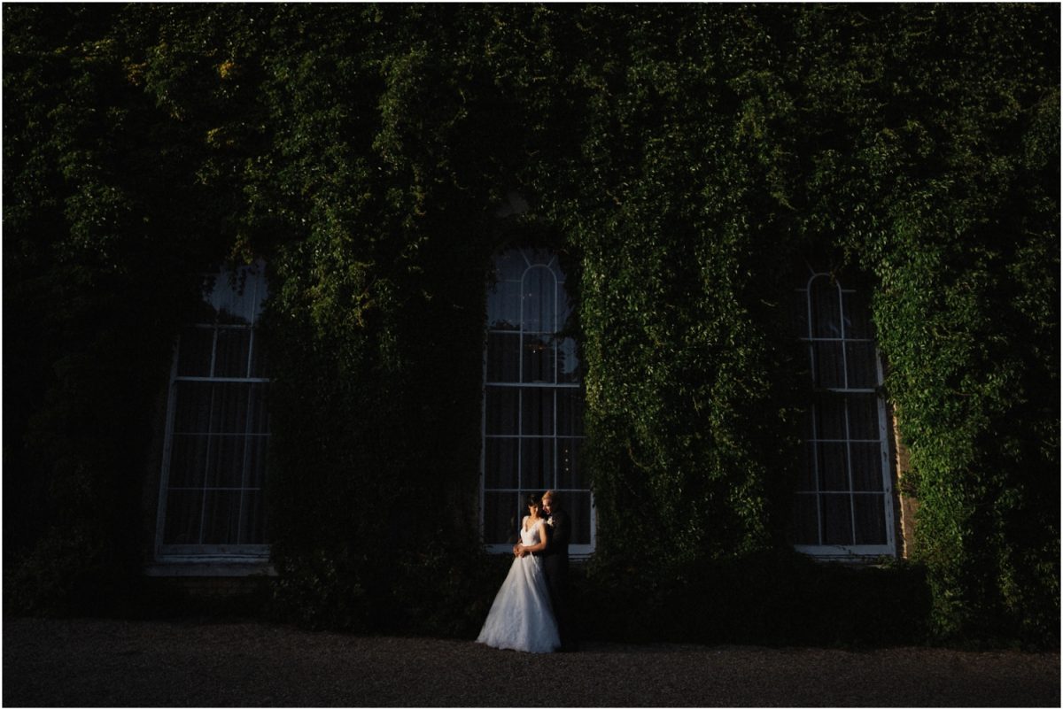 A newly married couple stand against an ivy covered wall at their Deve Beaumont Estate wedding