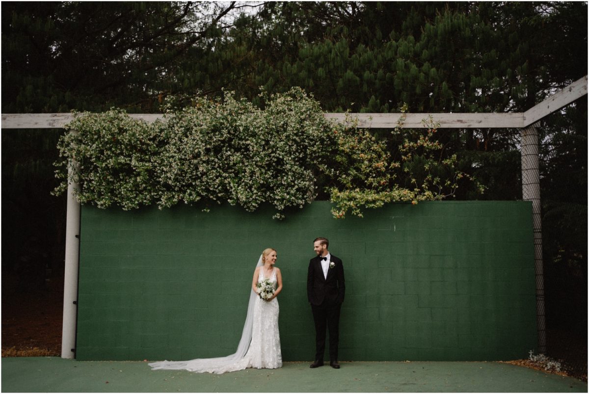 A newly married couple stand by a green wall at their Bowral Marquee Wedding