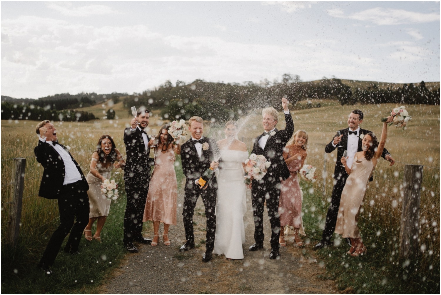 A newly married couple spray champagne at their Bendooley Estate Stables wedding
